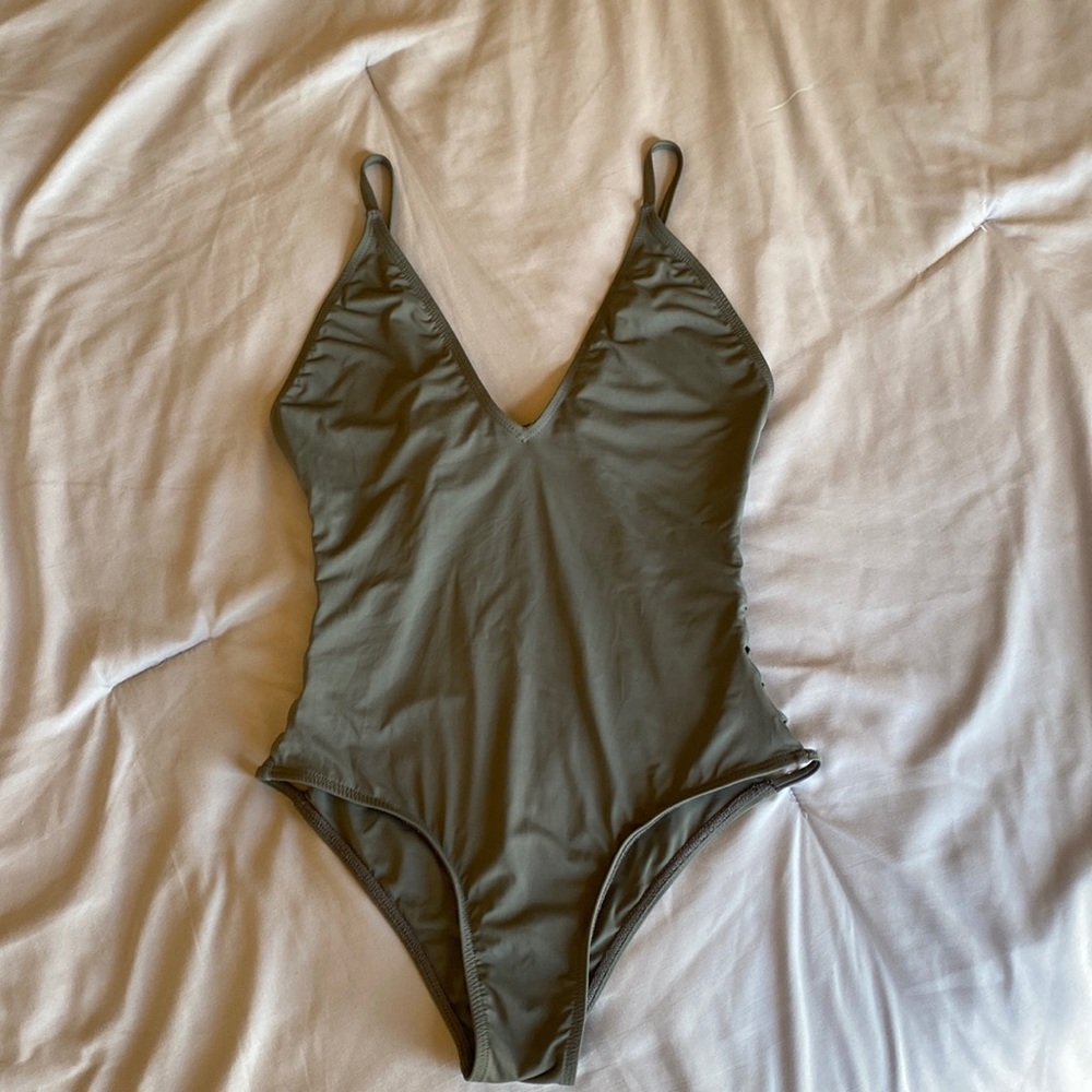 Green one piece, v neck scrappy sides, cheeky cut bottoms. Size S